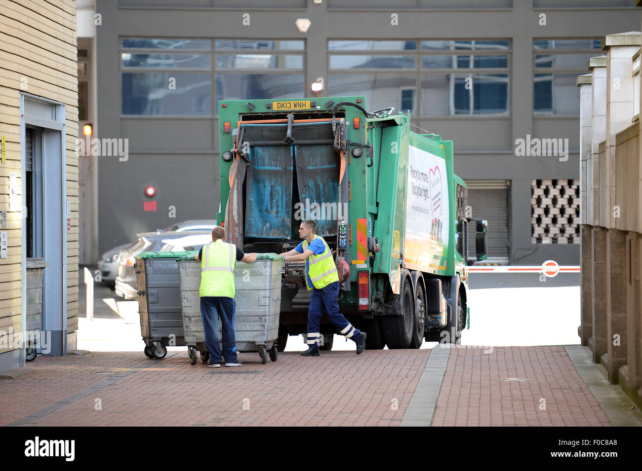 Refuse collectors emptying industrial wheelie bins in Manchester City Centre Stock Photo
