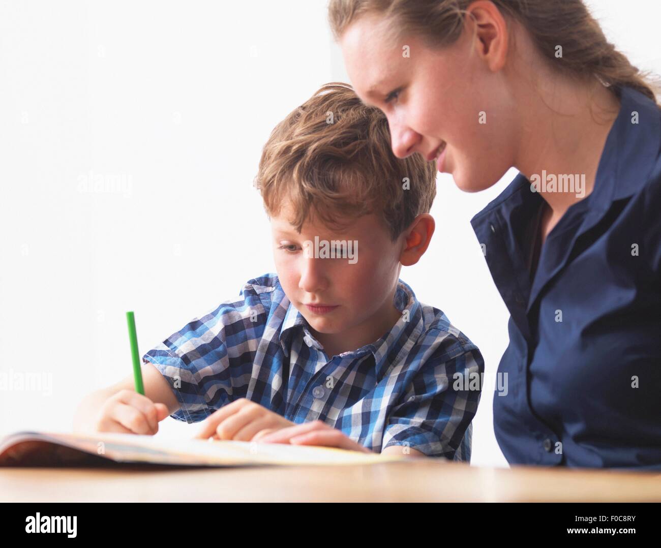 A six year old boy doing his homework with his mum at home Stock Photo