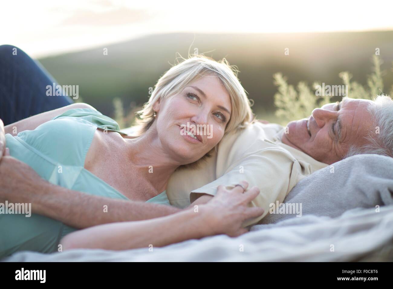 Mature couple lying together on blanket smiling Stock Photo - Alamy