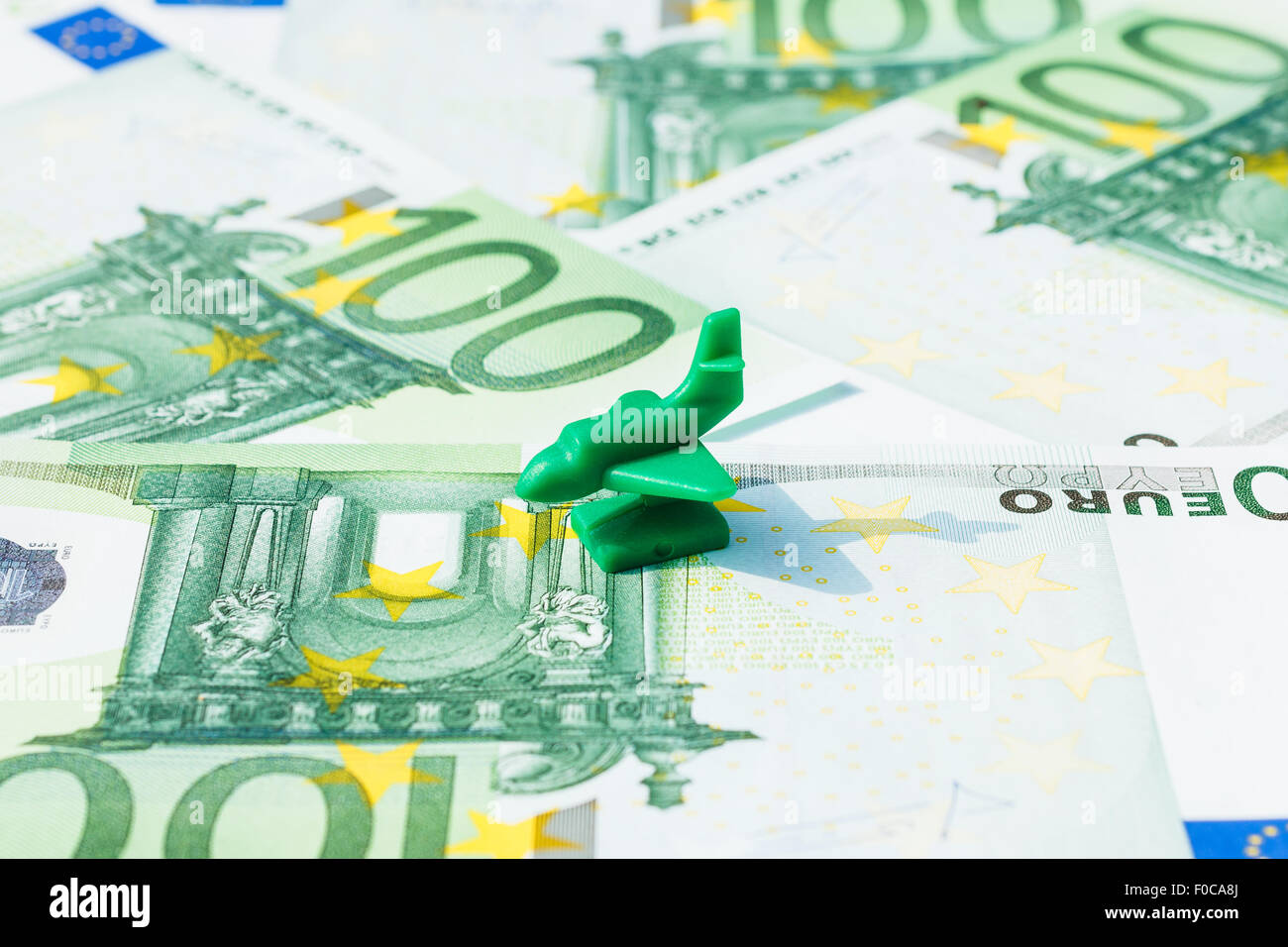Concept travel, vacation, holiday, salary, savings, transport on hundred euro banknotes. Focus on green airplane, jet. Stock Photo