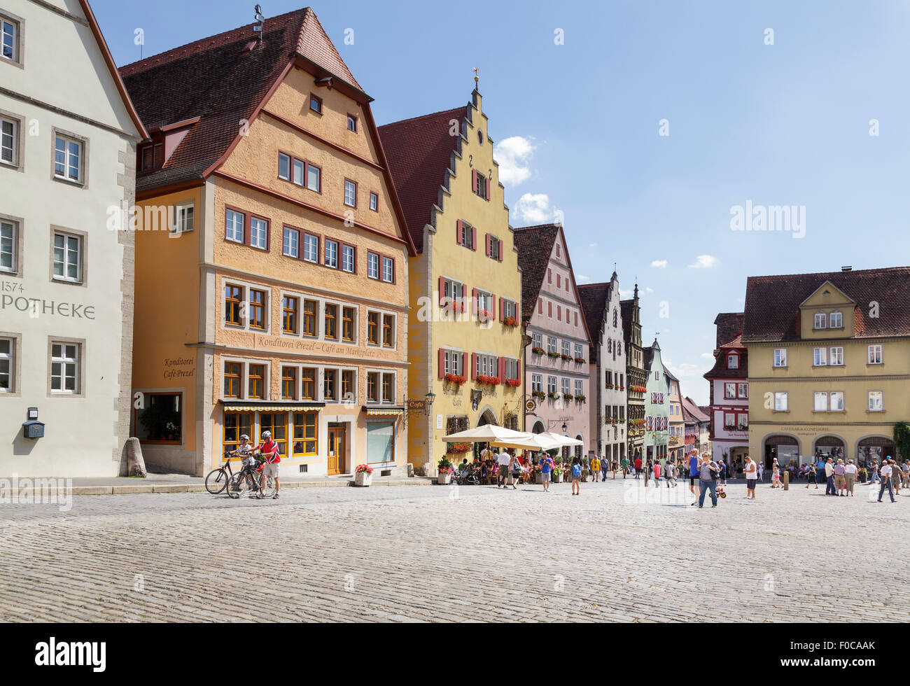 Tourists walking by typical buildings on the Marktplatz  Market Square, Rothenburg ob der Tauber, Franconia, Bavaria, Germany Stock Photo