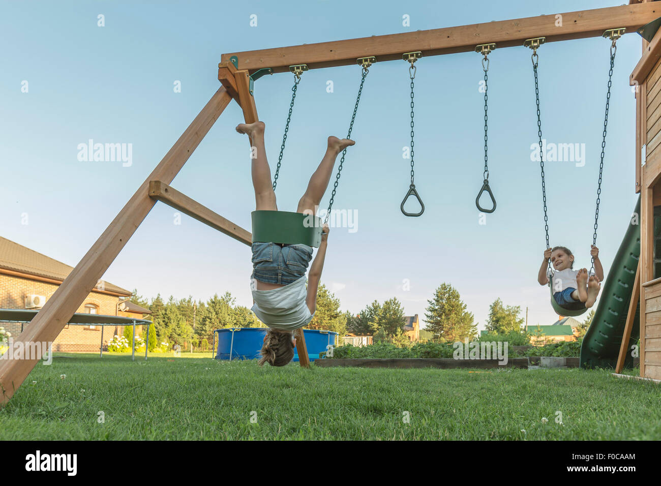 Girl performing stunts while swinging with sister in lawn Stock Photo