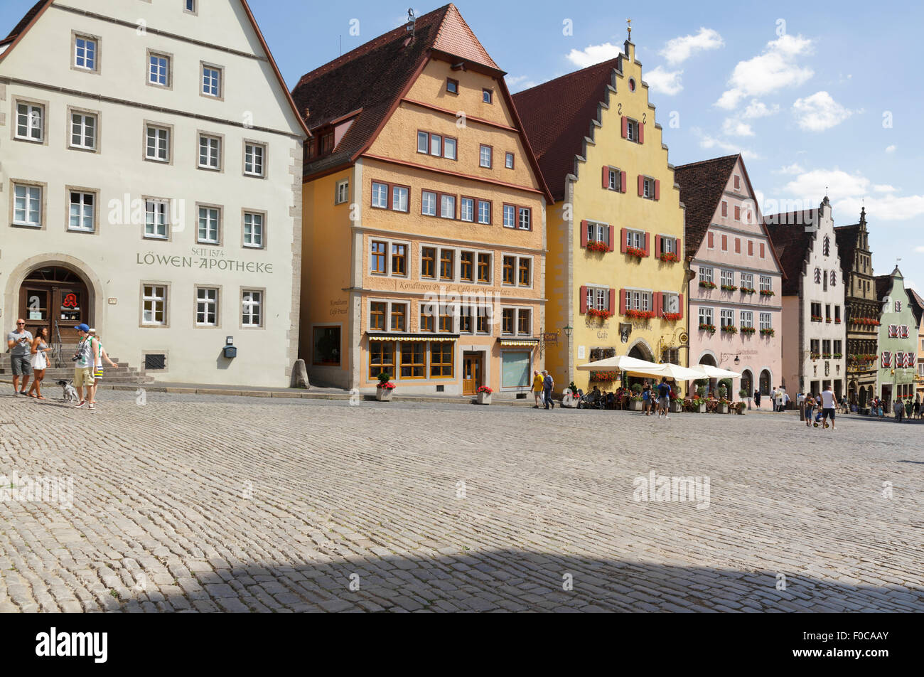 Tourists walking by typical buildings on the Marktplatz  Market Square, Rothenburg ob der Tauber, Franconia, Bavaria, Germany Stock Photo