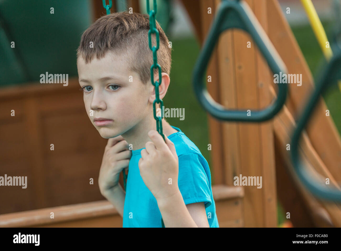 Thoughtful young boy swinging in yard Stock Photo