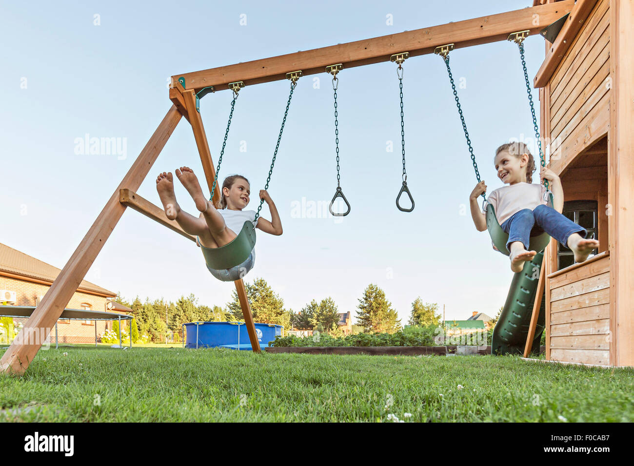 Happy sisters looking at each other while swinging in lawn Stock Photo