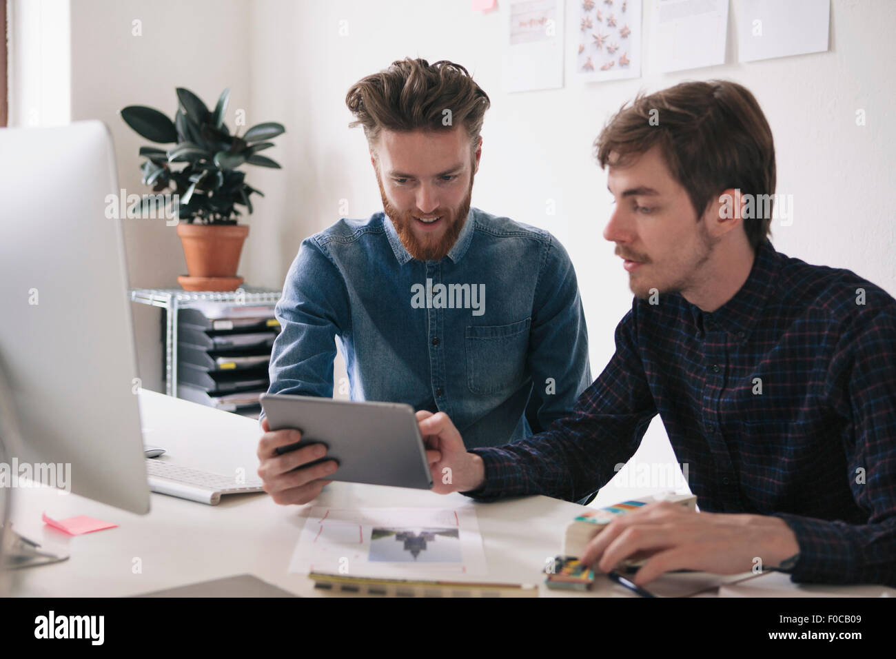 Young businessmen using digital tablet together at desk Stock Photo