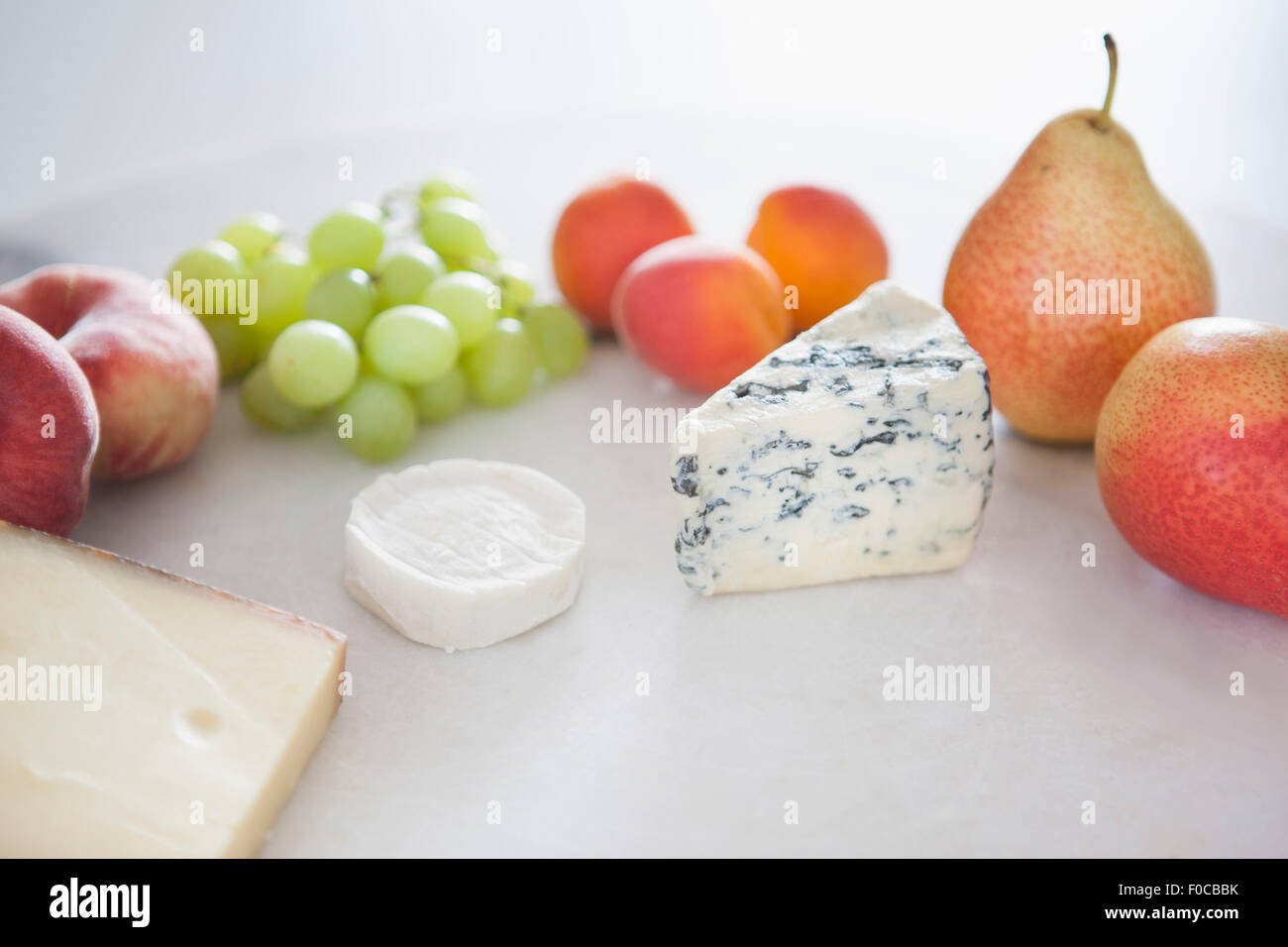 Fruits and cheese in plate against white background Stock Photo