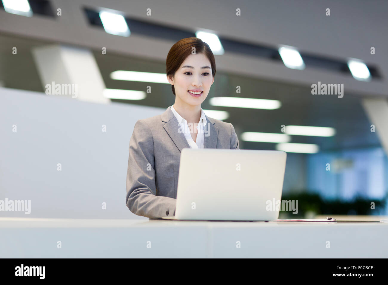 Confident receptionist using laptop at reception counter Stock Photo ...