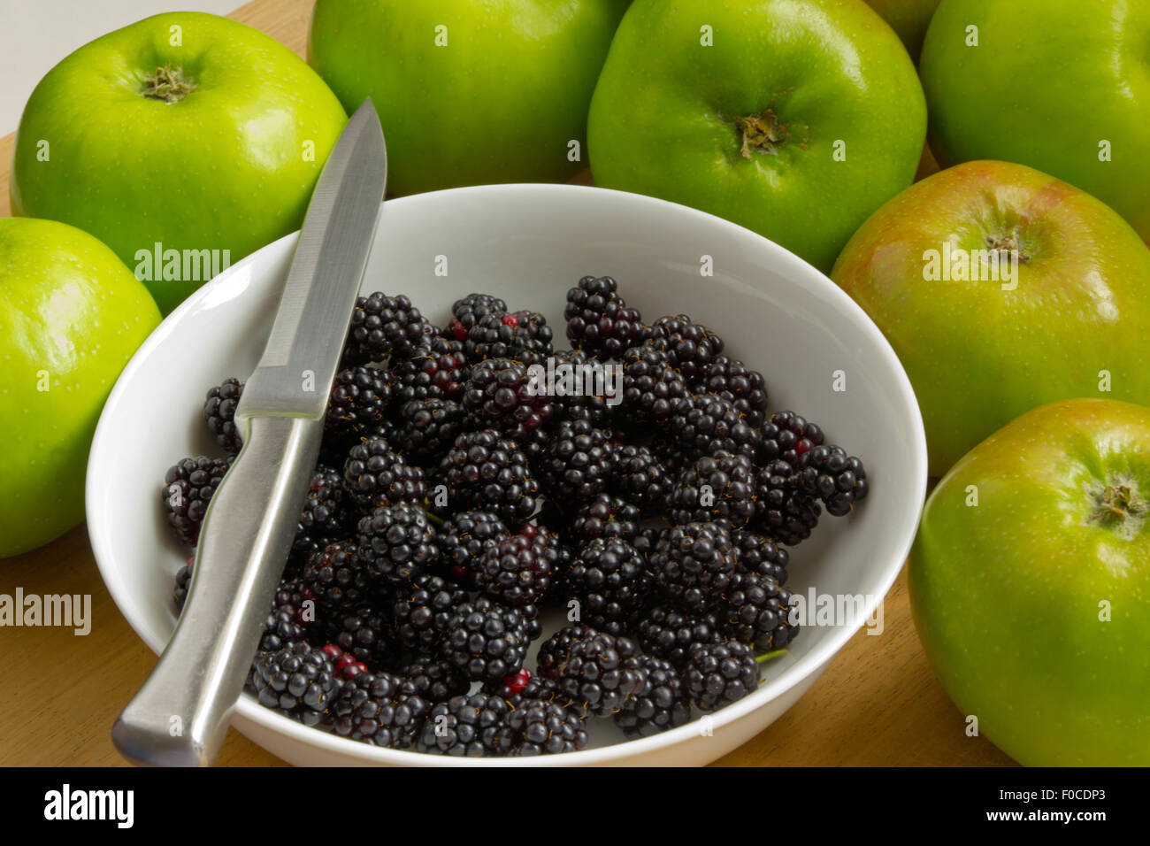 Blackberries in white bowl with knife with Bramley's  Apples surrounding Stock Photo