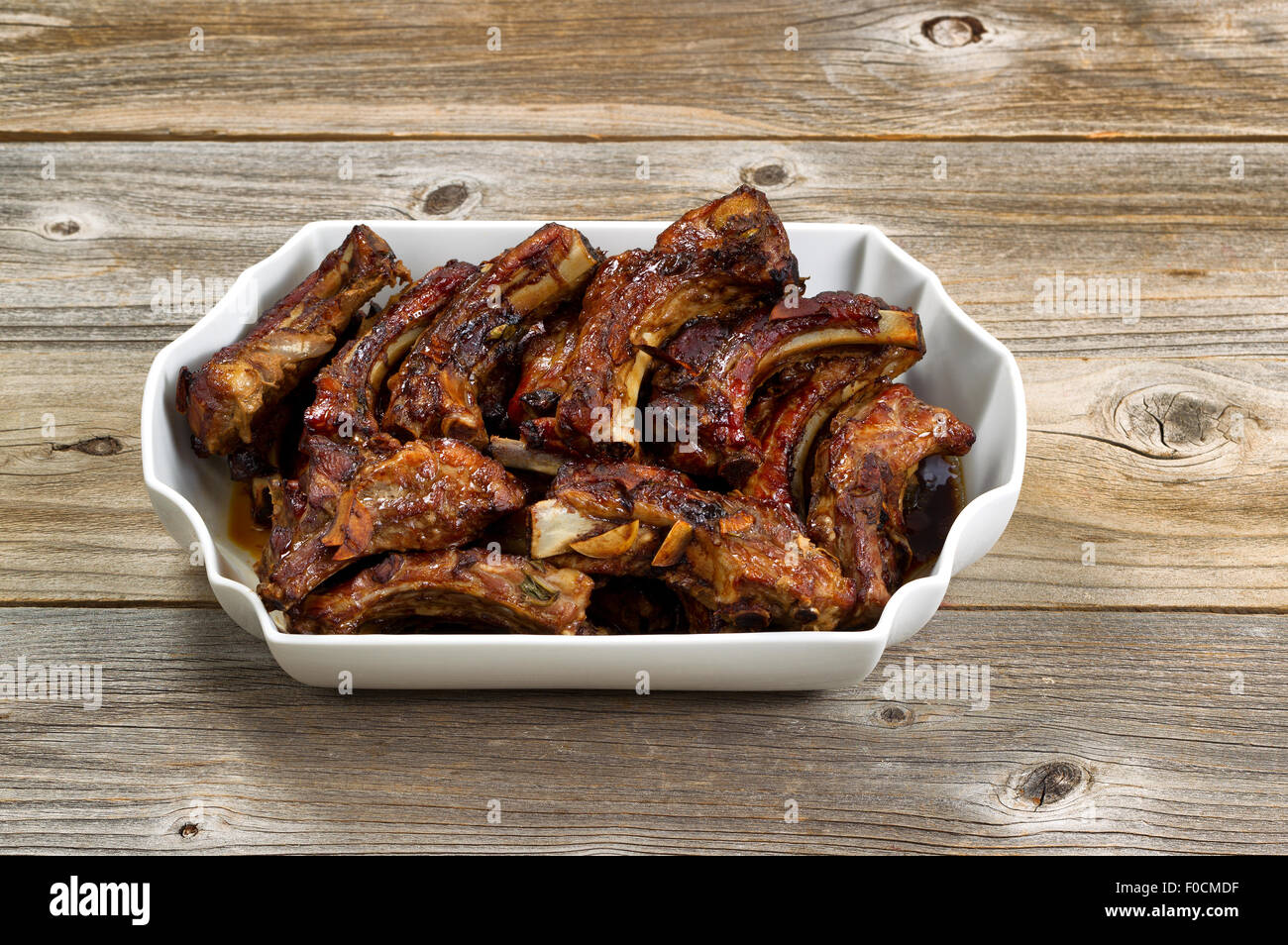 Large plate filled with delicious baked barbecued ribs on rustic wood. Stock Photo