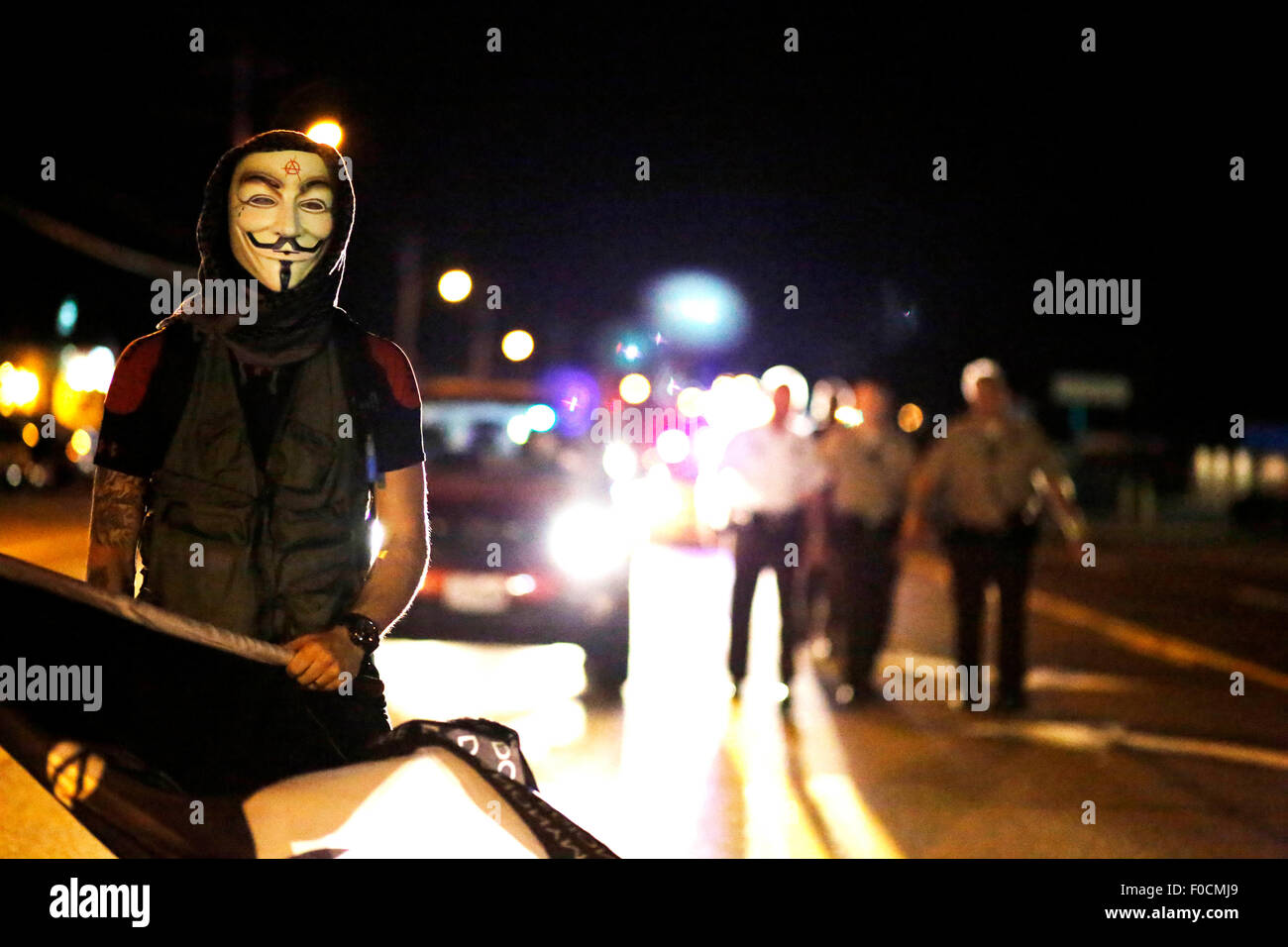 Ferguson, USA. 11th Aug, 2015. A protester moves away from approaching policemen during a manifestation in Ferguson, the United States, on Aug. 11, 2015. Protests marking the anniversary of the shooting of unarmed 18-year-old Michael Brown were extended for a second day on Tuesday in Ferguson. A state of emergency has been declared for the city of Ferguson on Monday, following gun battles between police and protestors Sunday night. © Jim Vondruska/Xinhua/Alamy Live News Stock Photo