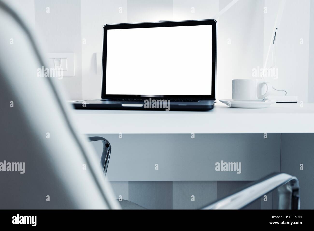 Modern Office Workstation with Laptop Computer. White Furnished Office Space. Stock Photo
