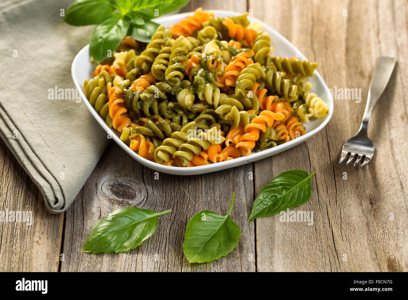 Fresh pasta with and fusilli noodles and basil pesto, selective focus on front part of dish. Stock Photo