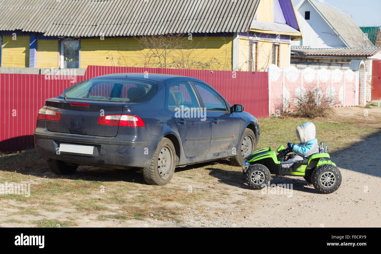 the little boy in warm overalls quickly goes by the car Stock Photo