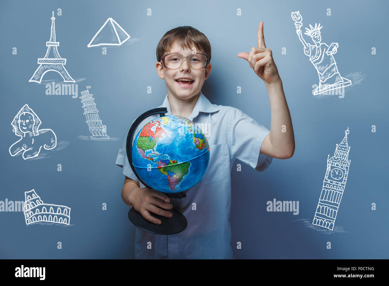 a boy of 10 years of European appearance with glasses holding a globe in hands  on a gray  background Stock Photo