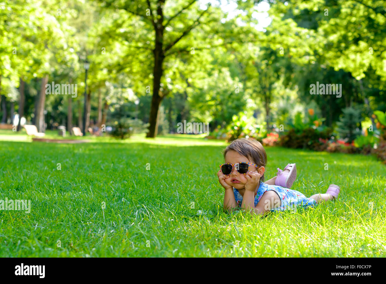 Cute little toddler girl laying in the grass on a sunny summer day ...