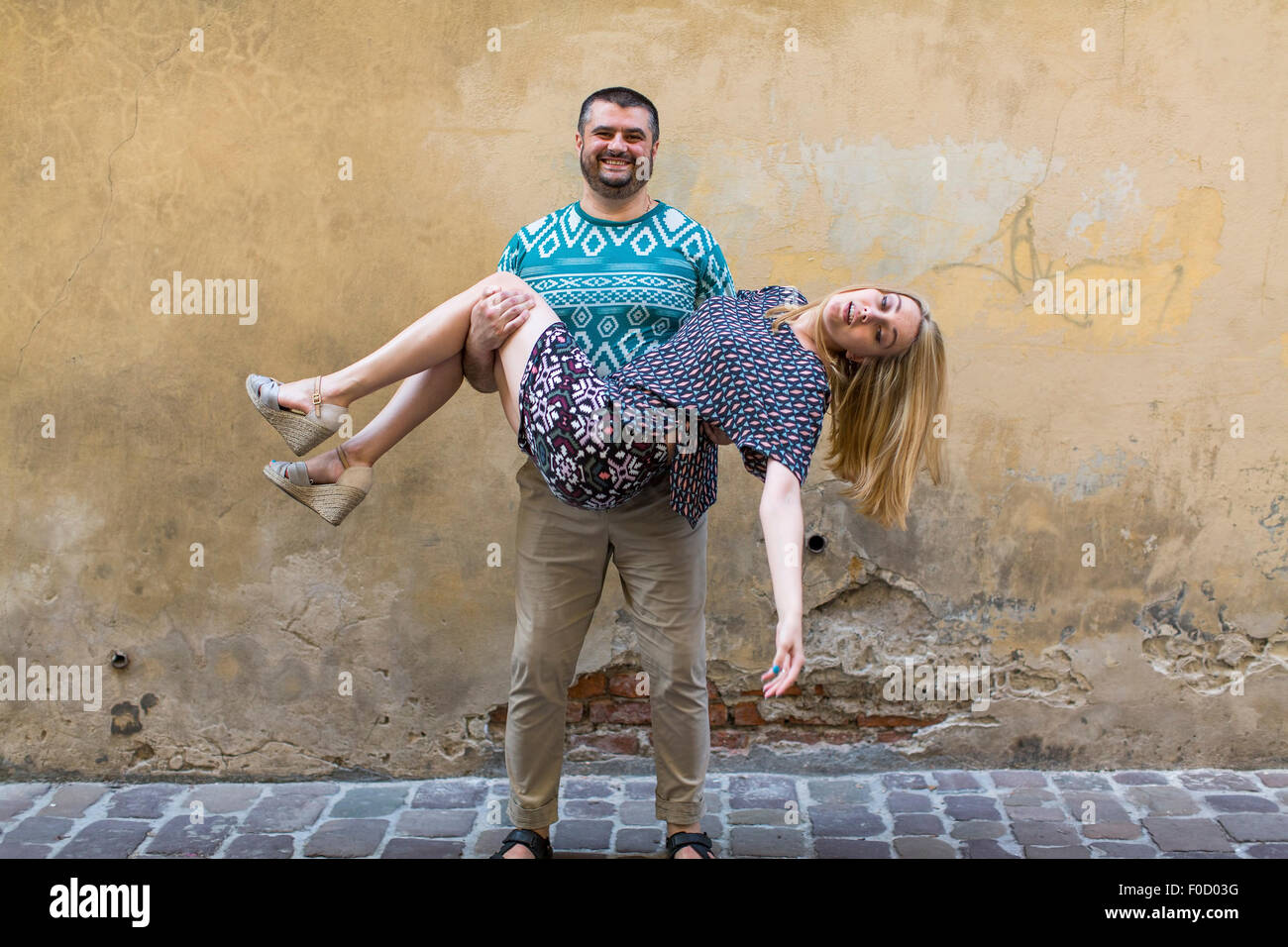 Happy fun couple in love on the street in front of a stone wall. Stock Photo