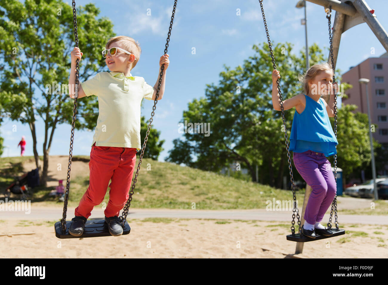 two happy kids swinging on swing at playground Stock Photo Alamy
