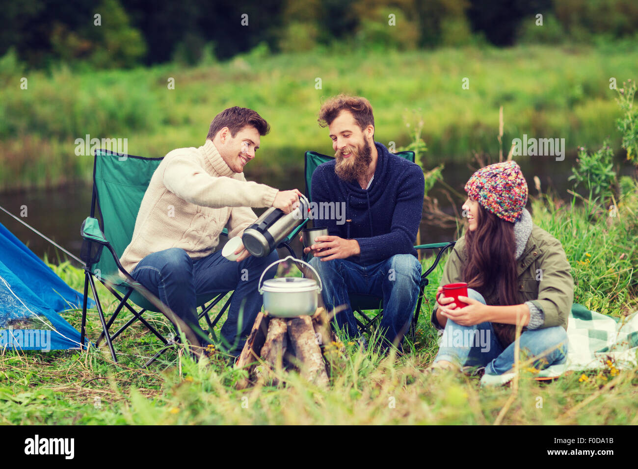group of smiling tourists cooking food in camping Stock Photo