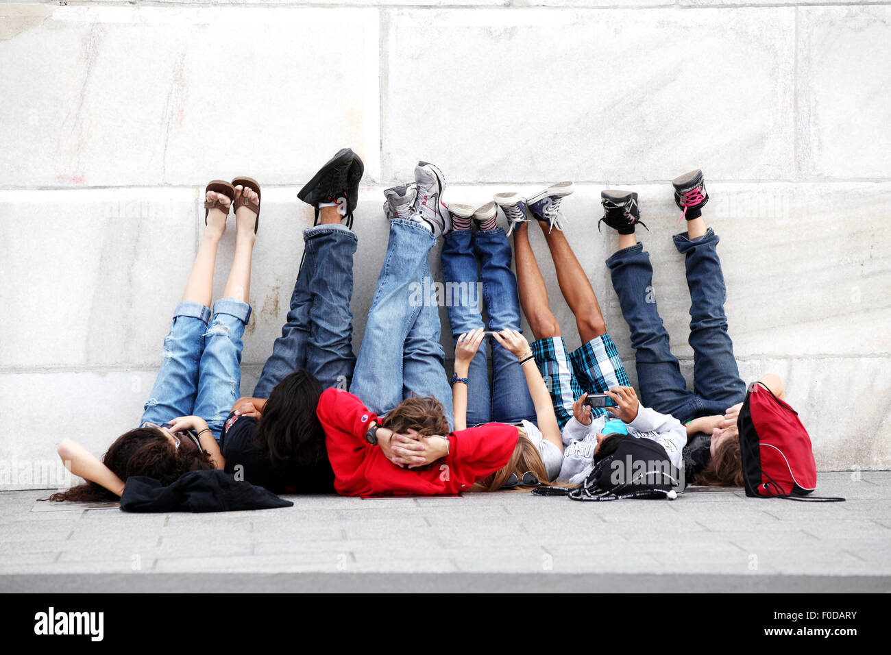 A group of youths having fun lying on their backs and looking up at the Washington Monument. their legs and feet at resting against the monument Stock Photo