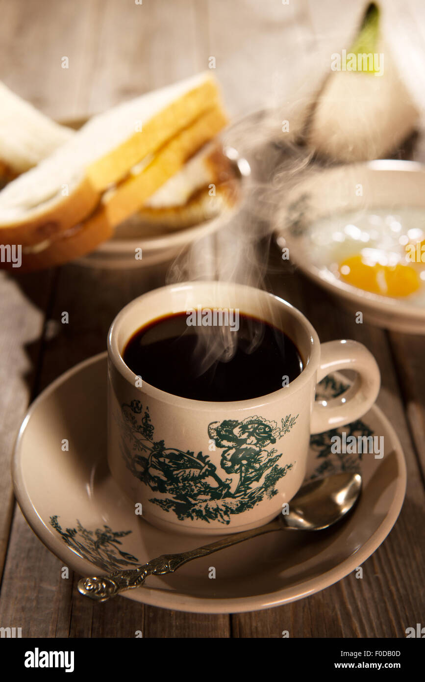 Traditional kopitiam style Malaysian coffee and breakfast with morning sunlight. Fractal on the cup is generic print. Soft focus Stock Photo