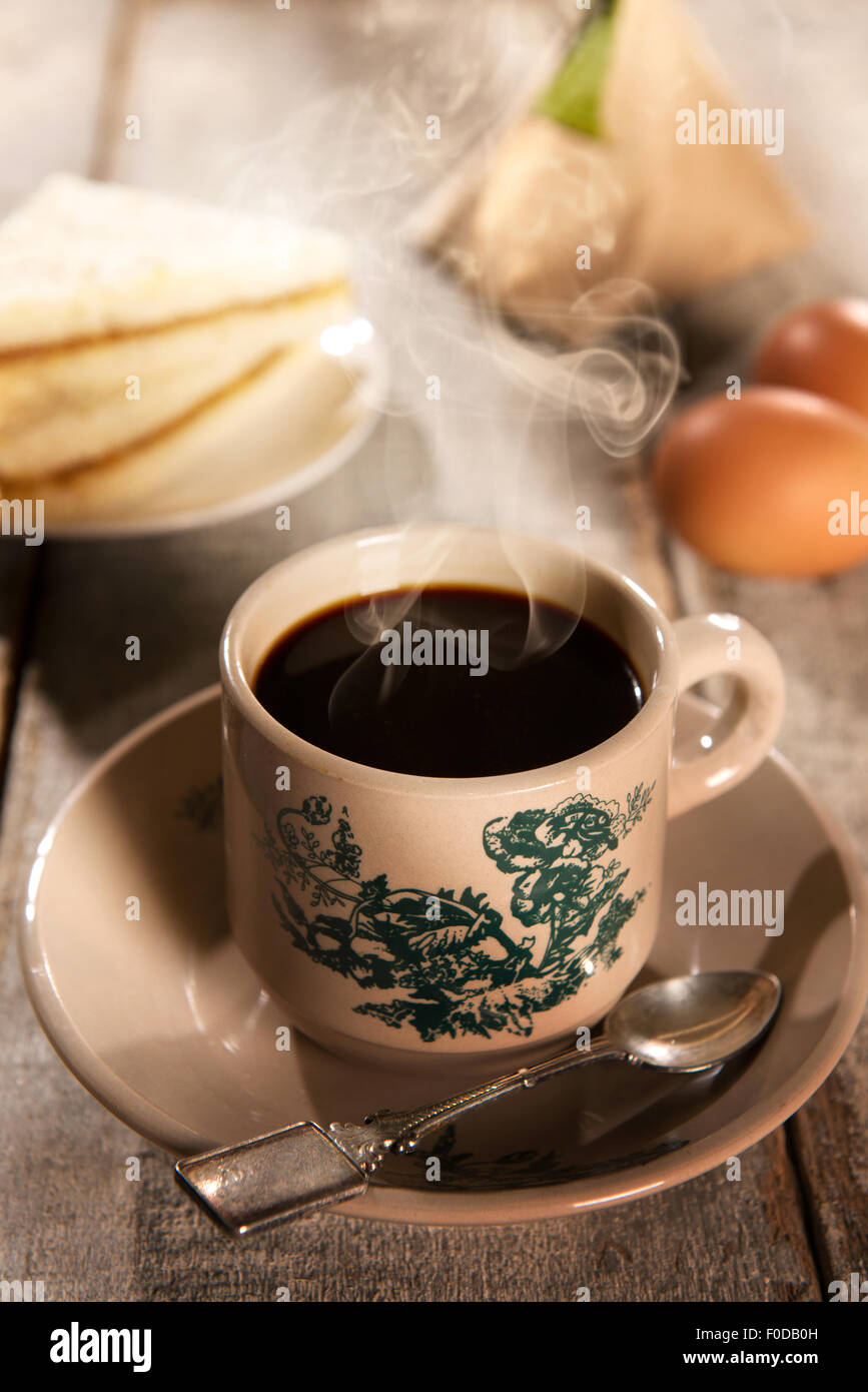 Traditional kopitiam style Malaysian coffee and breakfast with morning sunlight. Fractal on the cup is generic print. Soft focus Stock Photo