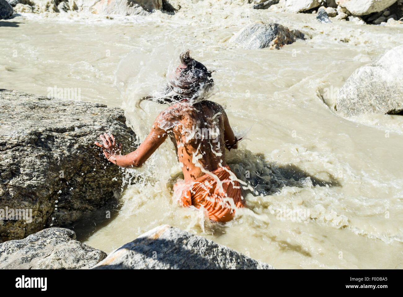 A Sadhu, holy man, is taking bath in the freezing cold water at Gaumukh, the main source of the holy river Ganges, Gangotri Stock Photo