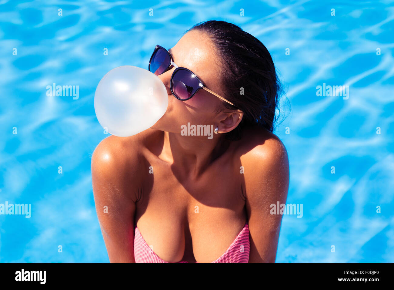 Woman blowing bubble with gum in swim pool outdoors Stock Photo