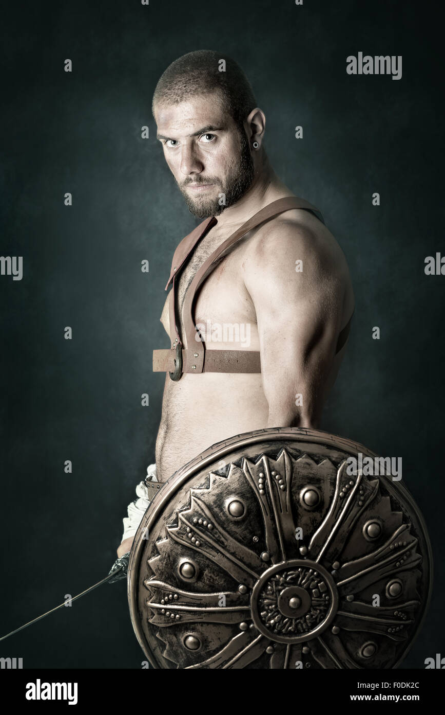 Gladiator posing with shield and sword in a dark background Stock Photo ...