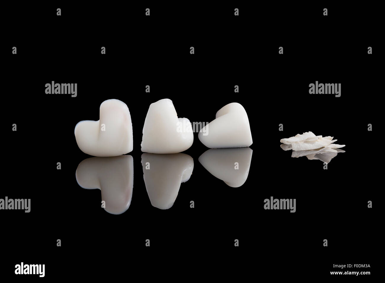 Hard coconut oil in heart shape and dry coconut flakes isolated on