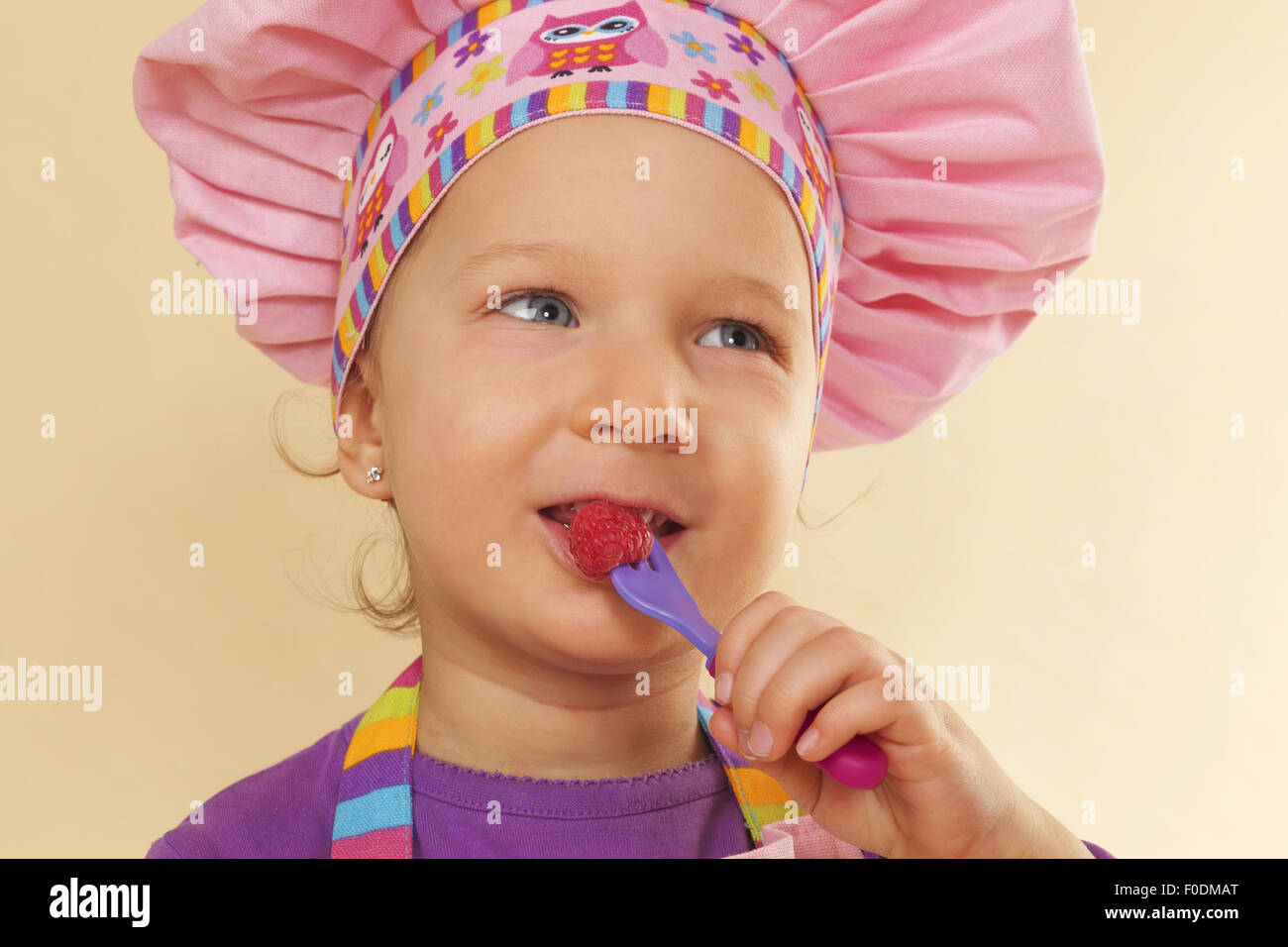 A Little Girl Eating Raspberries in a Kitchen · Free Stock Photo