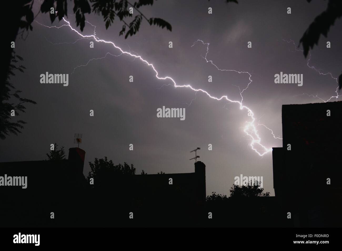 Forked lightning apparently striking a house at night in summer, UK Stock Photo