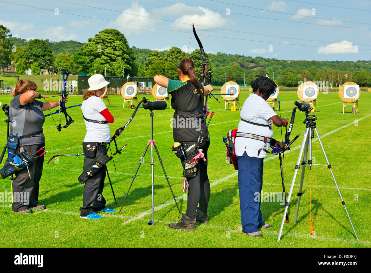 Row of women archers in line shooting various style bows in competition Stock Photo