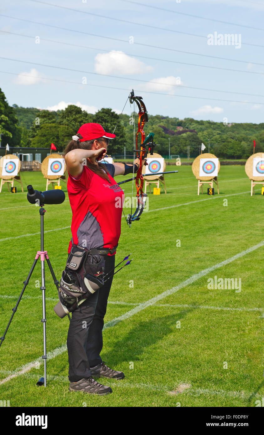 Woman shooting a compound bow in archery competition. Rowdon Meadows, Apperley Bridge, Bradford, West Yorkshire. Stock Photo