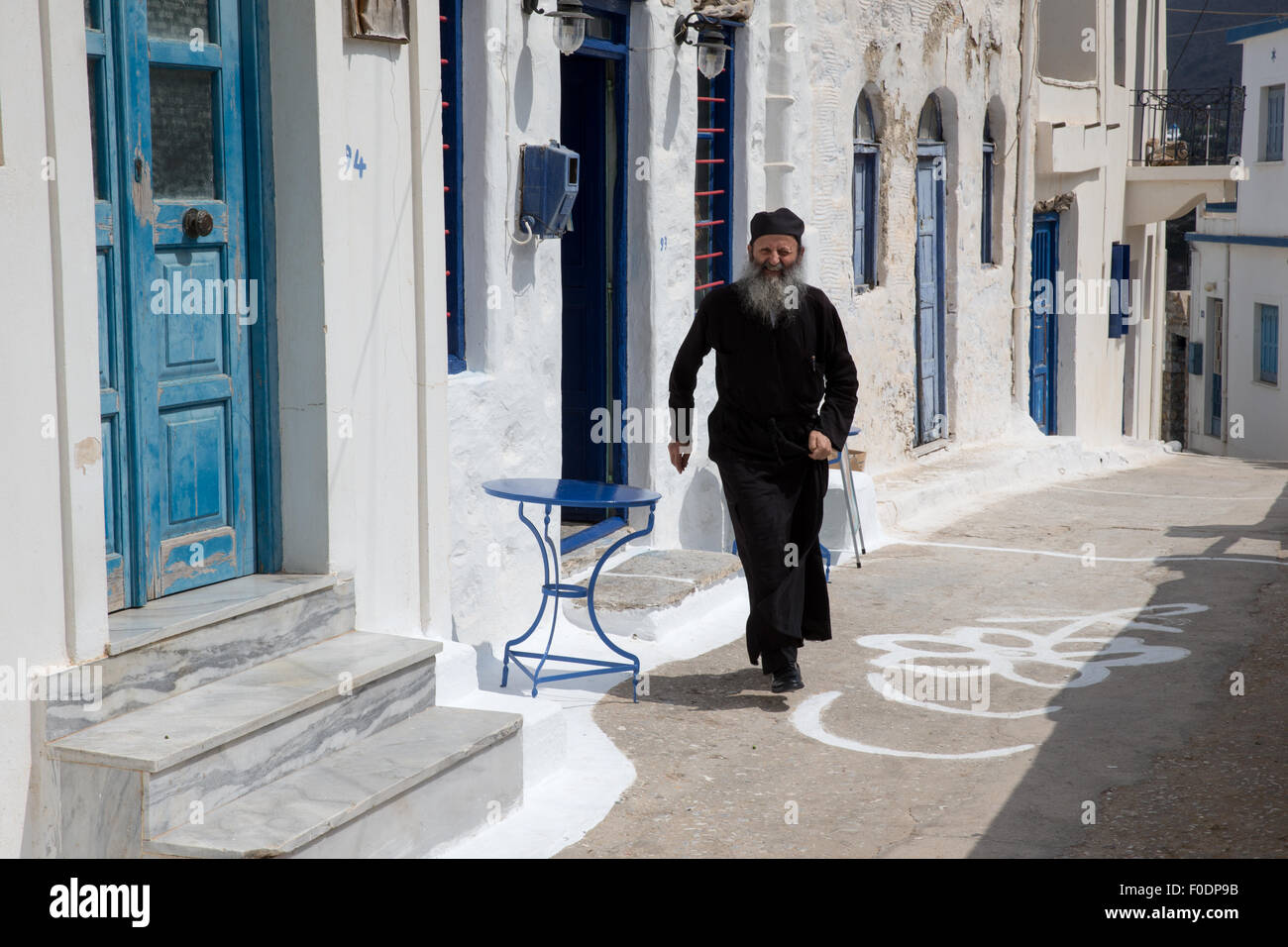 Greek Orthodox priest in whitewashed street in Greece Stock Photo