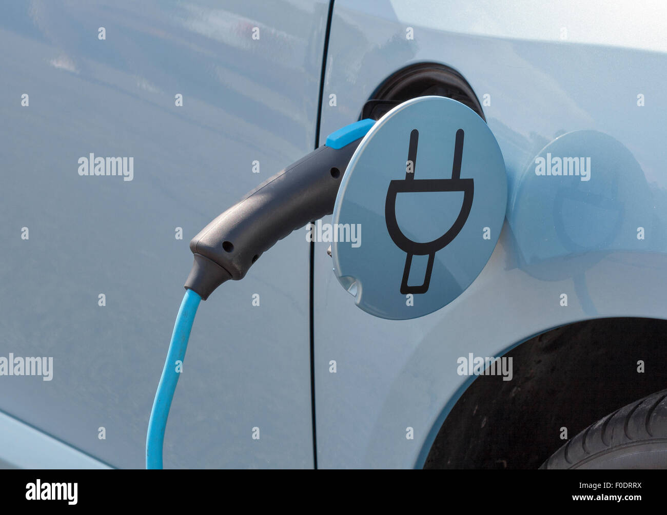 Charging an electric car with the power cable supply plugged in, closeup Stock Photo