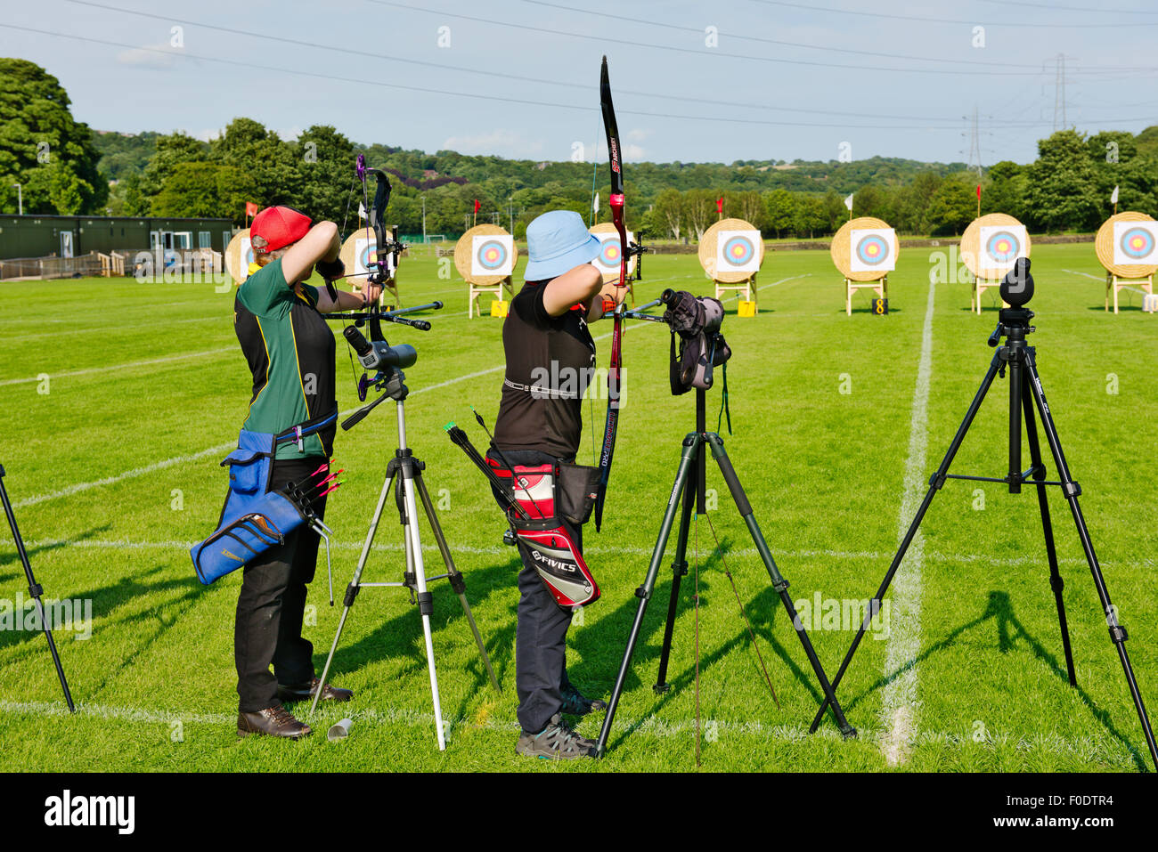 Two women archers in line shooting different styles of modern bows (compound and recurve) in competition, West Yorkshire, Englan Stock Photo