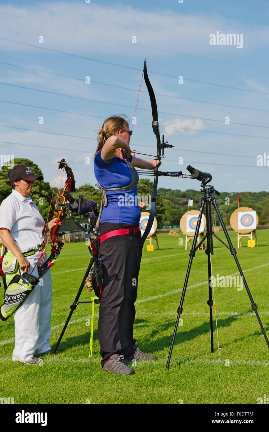 Two women archers in line shooting different styles of modern bows (compound and recurve) in competition, West Yorkshire, Englan Stock Photo