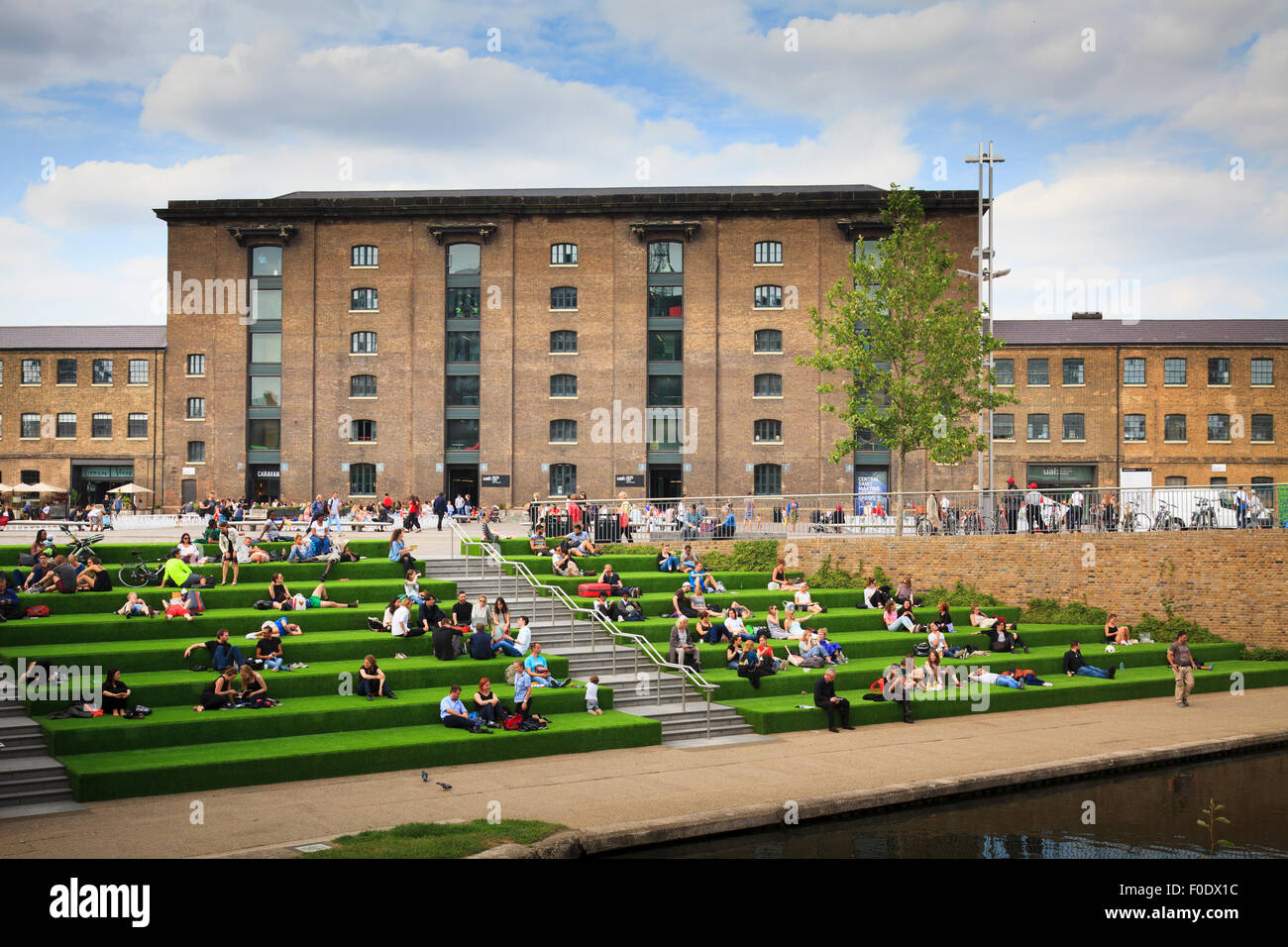 Students sitting on steps alongside the Regent's Canal in front of Central Saint Martins Stock Photo