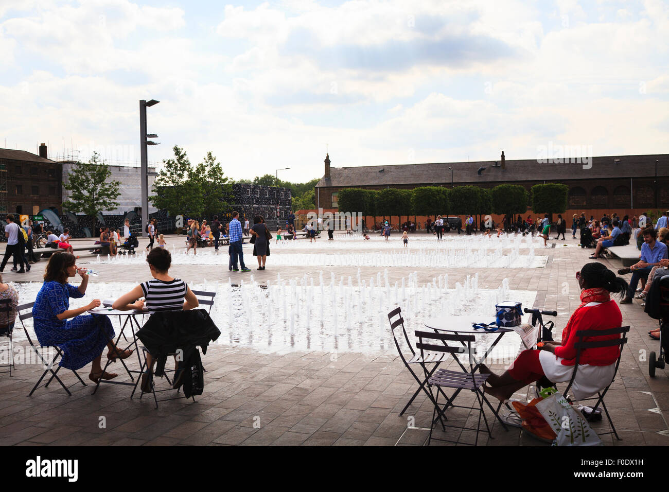People sit around the fountains in Granary Square outside Central Saint Martins Stock Photo