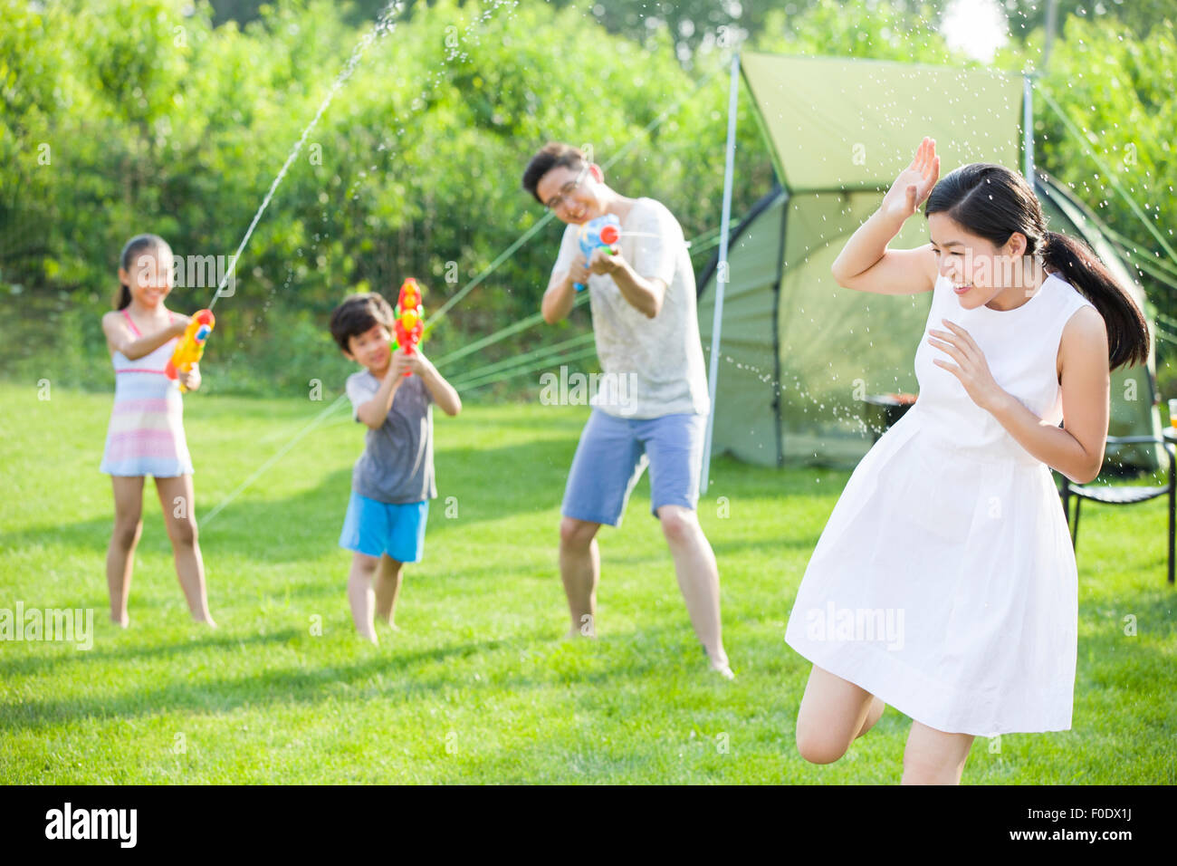 Happy young family playing squirt guns Stock Photo