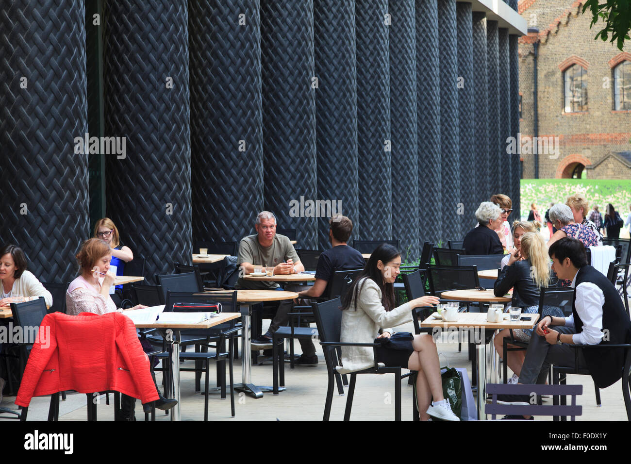 People sit at street cafe at St Pancras in amongst modern architectural pillars Stock Photo