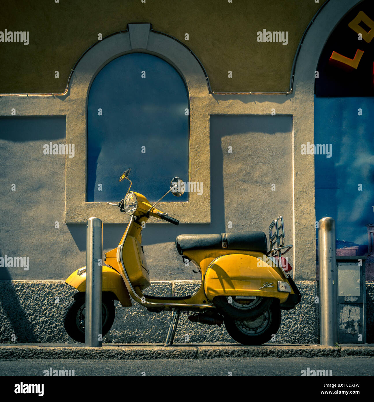 Yellow scooter parked on the pavement outside a canalside restaurant, Naviglio region of Milan Stock Photo