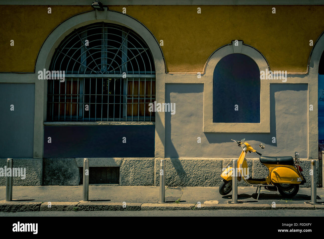 Yellow scooter parked outside a canalside restaurant, Naviglio region of Milan Stock Photo