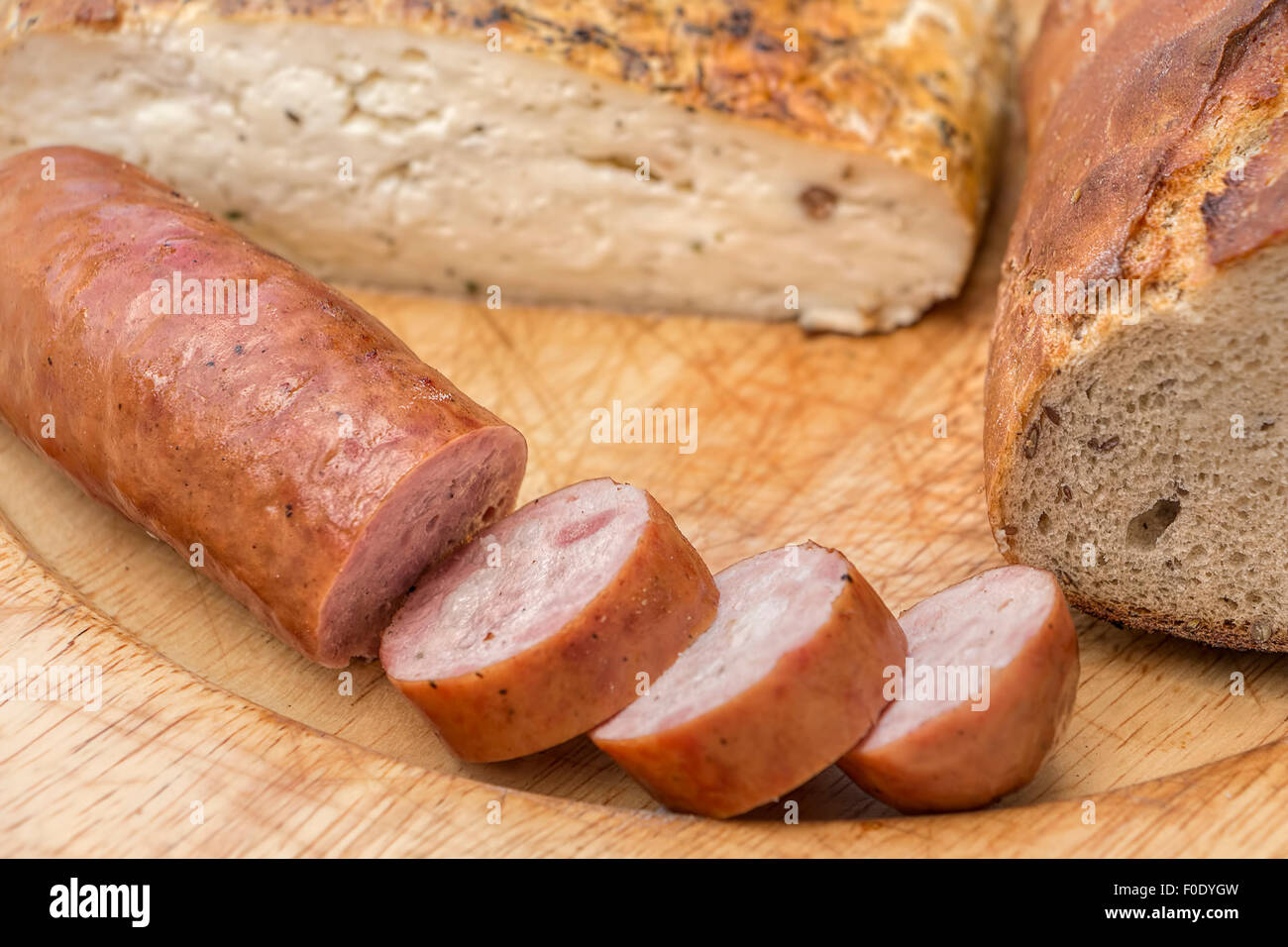 Homemade sausage, bread and cheese on rustic wooden dish. Stock Photo