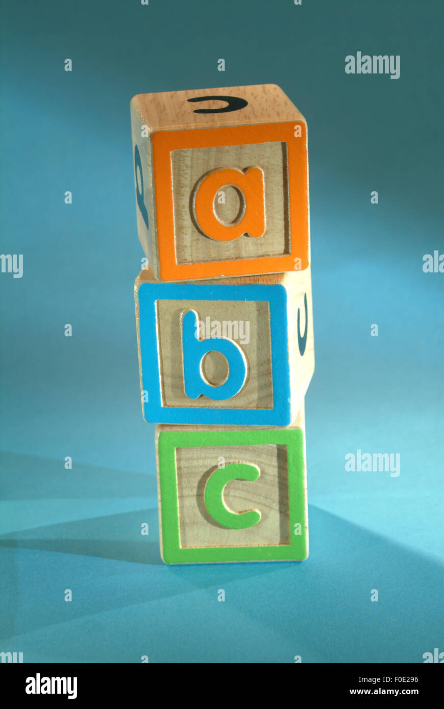 Small child's alphabet building blocks shot from the side on a turquoise background Stock Photo
