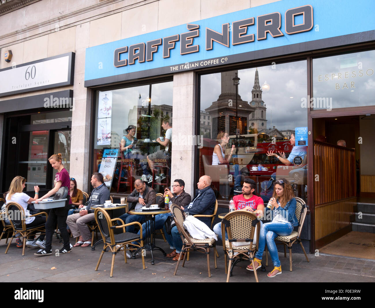 Coffee shop exterior UK; People sitting outside the Caffe Nero coffee shop, Trafalgar Square, London UK Stock Photo