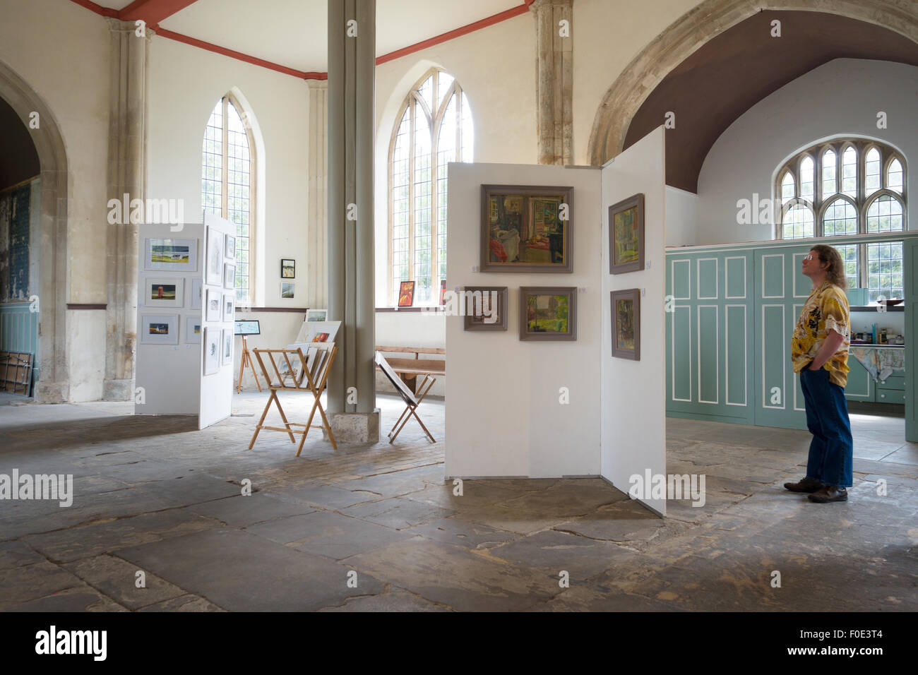 A man looking at paintings in a local village art exhibition in a country church, Swaffham Prior village , Cambridgeshire UK Stock Photo