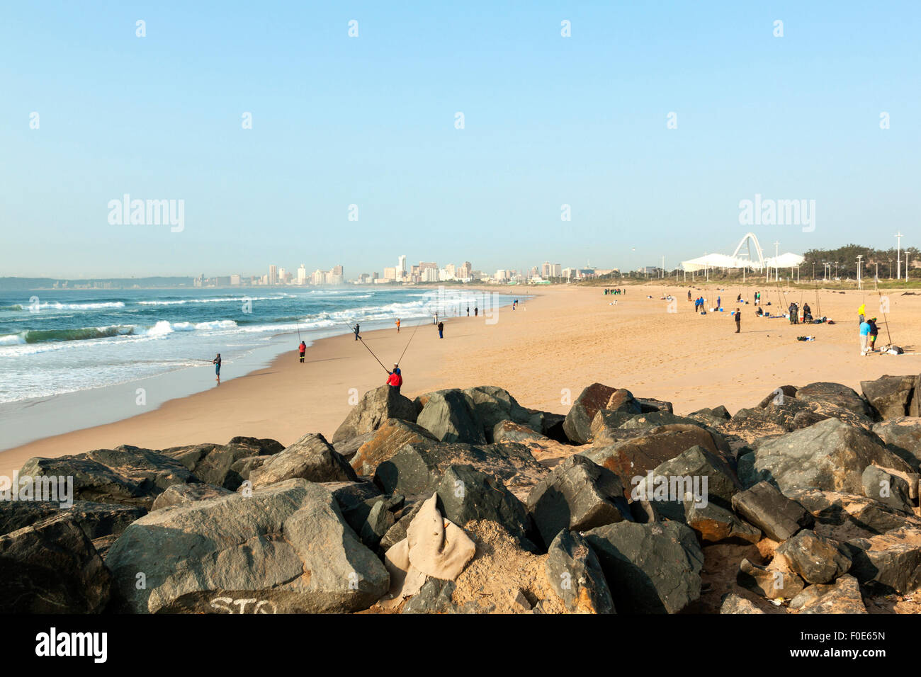 Many unknown fishermen on Blue Lagoon beach against Durban city skyline