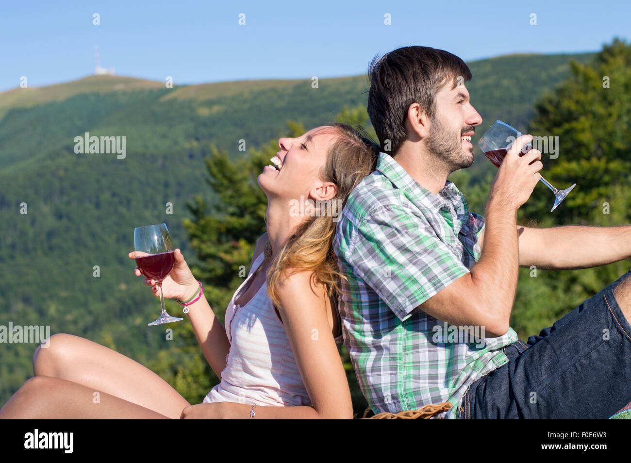 Young happy couple drinking wine on a hiking trip at the viewpoint. Couple hiking trip Stock Photo